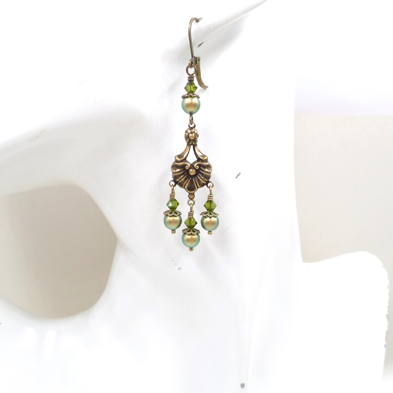 shimmery green pearls are paired with olive crystals in these Victorian reproduction chandelier earrings, handmade by me.  The chandelier connectors have a floral motif in antique brass, and the ear wires are antique brass in a lever back style.