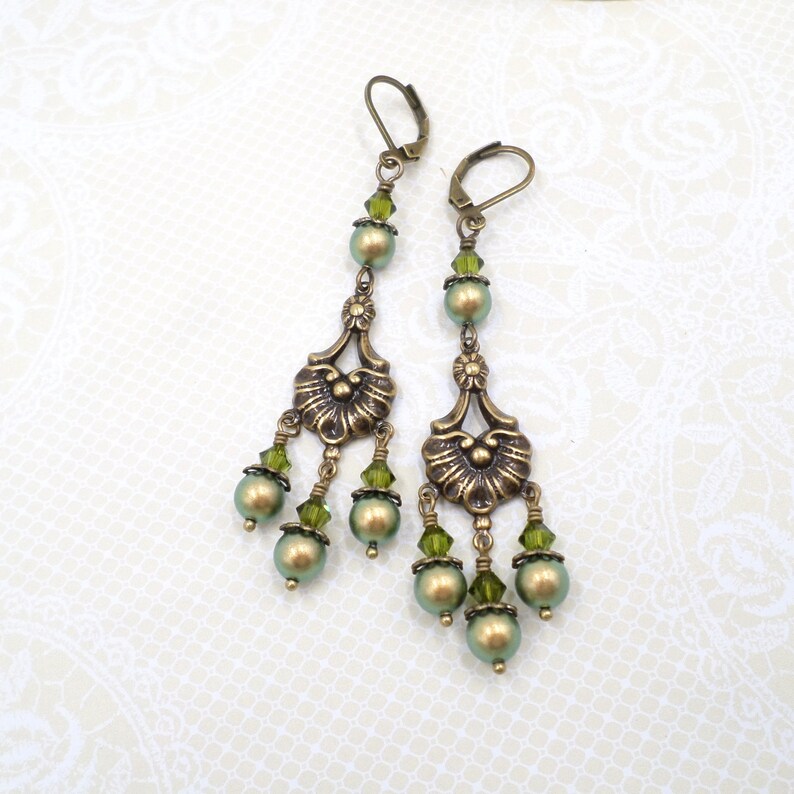 shimmery green pearls are paired with olive crystals in these Victorian reproduction chandelier earrings, handmade by me.  The chandelier connectors have a floral motif in antique brass, and the ear wires are antique brass in a lever back style.