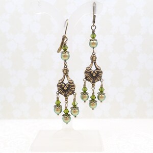 shimmery green pearls are paired with olive crystals in these Victorian reproduction chandelier earrings, handmade by me.  The chandelier connectors have a floral motif in antique brass, and the ear wires are antique brass in a lever back style.
