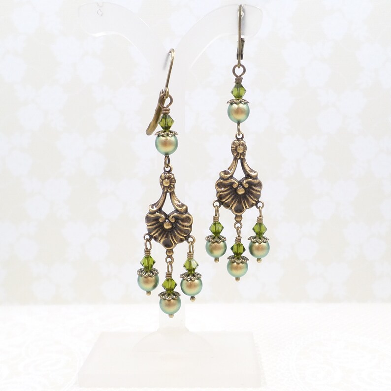shimmery green pearls are paired with olive crystals in these Victorian reproduction chandelier earrings, handmade by me.  The chandelier connectors have a floral motif in antique brass, and the ear wires are antique brass in a lever back style.