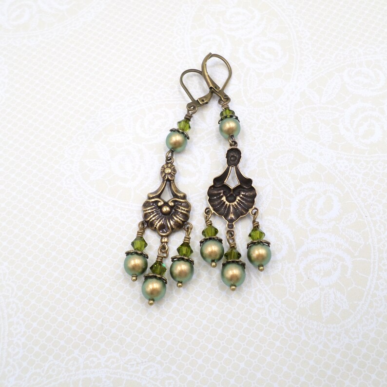 shimmery green pearls are paired with olive crystals in these Victorian reproduction chandelier earrings, handmade by me.  The chandelier connectors have a floral motif in antique brass, and the ear wires are antique brass in a lever back style.