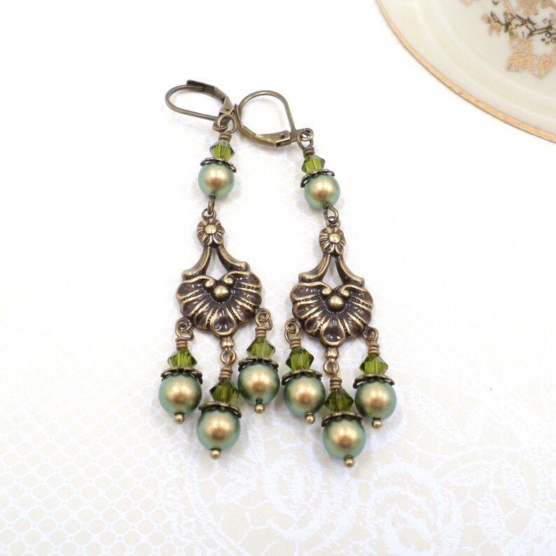 shimmery green pearls are paired with olive crystals in these Victorian reproduction chandelier earrings, handmade by me.  The chandelier connectors have a floral motif in antique brass, and the ear wires are antique brass in a lever back style.