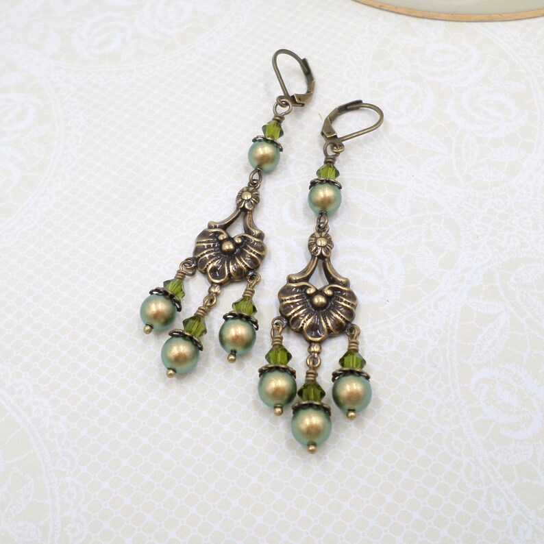 shimmery green pearls are paired with olive crystals in these Victorian reproduction chandelier earrings, handmade by me.  The chandelier connectors have a floral motif in antique brass, and the ear wires are antique brass in a lever back style.