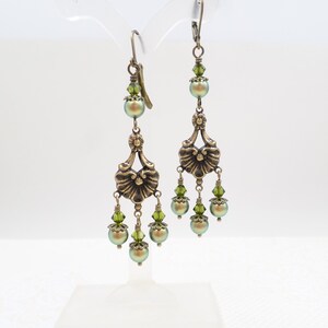 shimmery green pearls are paired with olive crystals in these Victorian reproduction chandelier earrings, handmade by me.  The chandelier connectors have a floral motif in antique brass, and the ear wires are antique brass in a lever back style.