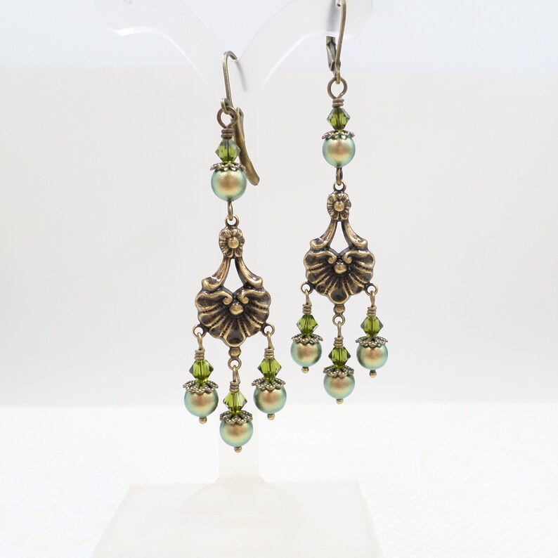 shimmery green pearls are paired with olive crystals in these Victorian reproduction chandelier earrings, handmade by me.  The chandelier connectors have a floral motif in antique brass, and the ear wires are antique brass in a lever back style.