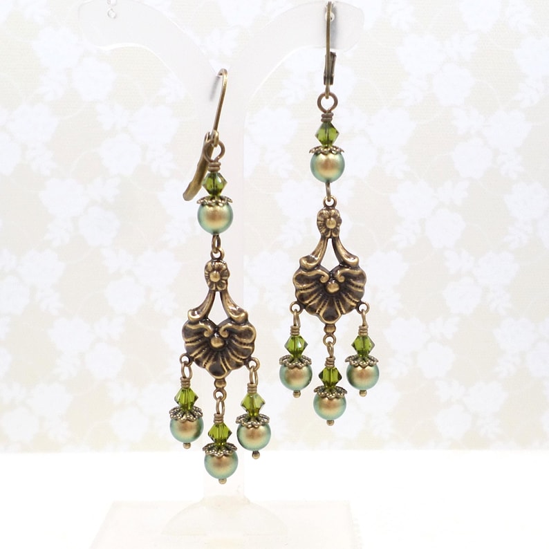 shimmery green pearls are paired with olive crystals in these Victorian reproduction chandelier earrings, handmade by me.  The chandelier connectors have a floral motif in antique brass, and the ear wires are antique brass in a lever back style.