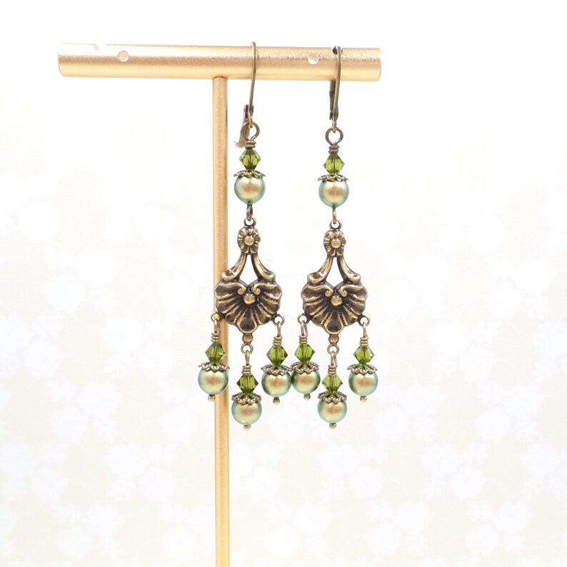 shimmery green pearls are paired with olive crystals in these Victorian reproduction chandelier earrings, handmade by me.  The chandelier connectors have a floral motif in antique brass, and the ear wires are antique brass in a lever back style.