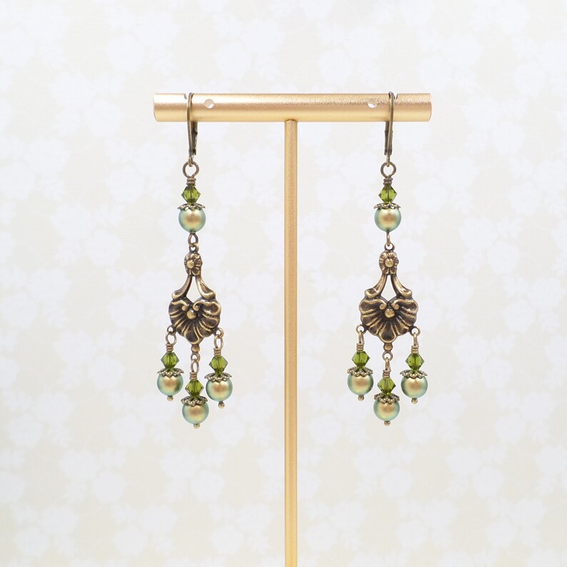 shimmery green pearls are paired with olive crystals in these Victorian reproduction chandelier earrings, handmade by me.  The chandelier connectors have a floral motif in antique brass, and the ear wires are antique brass in a lever back style.