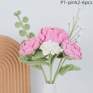 May include: A bouquet of six crocheted flowers in pink and white. The flowers are arranged in a vase and have green leaves.