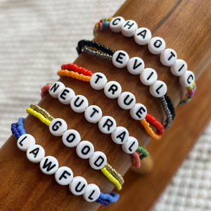 May include: A set of seven colourful beaded bracelets with white beads spelling out the words "Lawful", "Good", "Neutral", "True", "Evil", and "Chaotic".