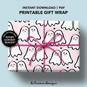 Puede incluir: Un regalo envuelto con un fondo rosa que presenta un patrón de fantasmas de dibujos animados blancos con lazos rosas y corazones negros. El regalo está atado con una cuerda rosa. El texto en el papel de regalo dice "Instant Download | PDF Printable Gift Wrap".