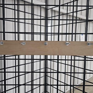 Może przedstawiać: Drewniana półka z pięcioma metalowymi śrubami przymocowanymi do czarnej siatki drucianej.