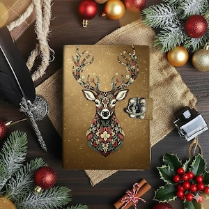 May include: A brown leather journal with a decorative deer design on the cover. The deer is adorned with floral patterns in red, green, and white. The journal has a metal clasp closure and is surrounded by Christmas decorations.