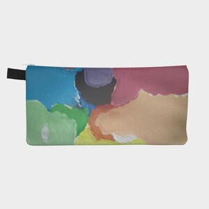 May include: A rectangular zippered pouch featuring an abstract design with large, irregular patches of blue, green, yellow, orange, pink, purple, and black. The fabric surface displays a smooth texture with a black zipper pull on the left side.