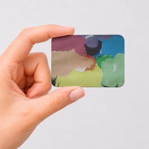 Peut inclure: Un aimant rectangulaire présentant un motif abstrait avec des taches de couleur superposées, notamment bordeaux, beige, vert citron, vert forêt, bleu foncé et noir. Les bords sont arrondis et la surface a une finition mate et lisse.