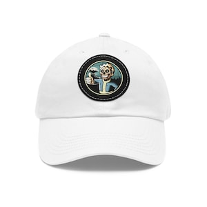 May include: White baseball cap with a black and white embroidered patch of a cartoon character with a skull face holding a beer and giving a thumbs up. The character is standing in front of a mushroom cloud.