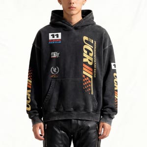 May include: A black hoodie with racing-themed graphics and patches, paired with black leather pants and boots. The hoodie features the number "11" and the text "UCR" in gold and red. The pants have quilted knee panels.