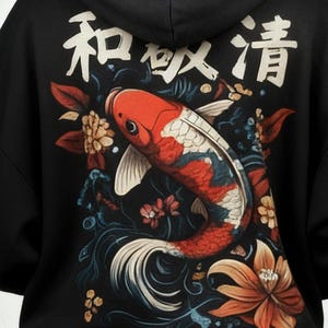 Pu&ograve; includere: Felpa con cappuccio nera con un'illustrazione di una carpa koi con scaglie rosse, bianche e blu, circondata da elementi floreali. Caratteri giapponesi e la parola "Nishikigoi" sono stampati.