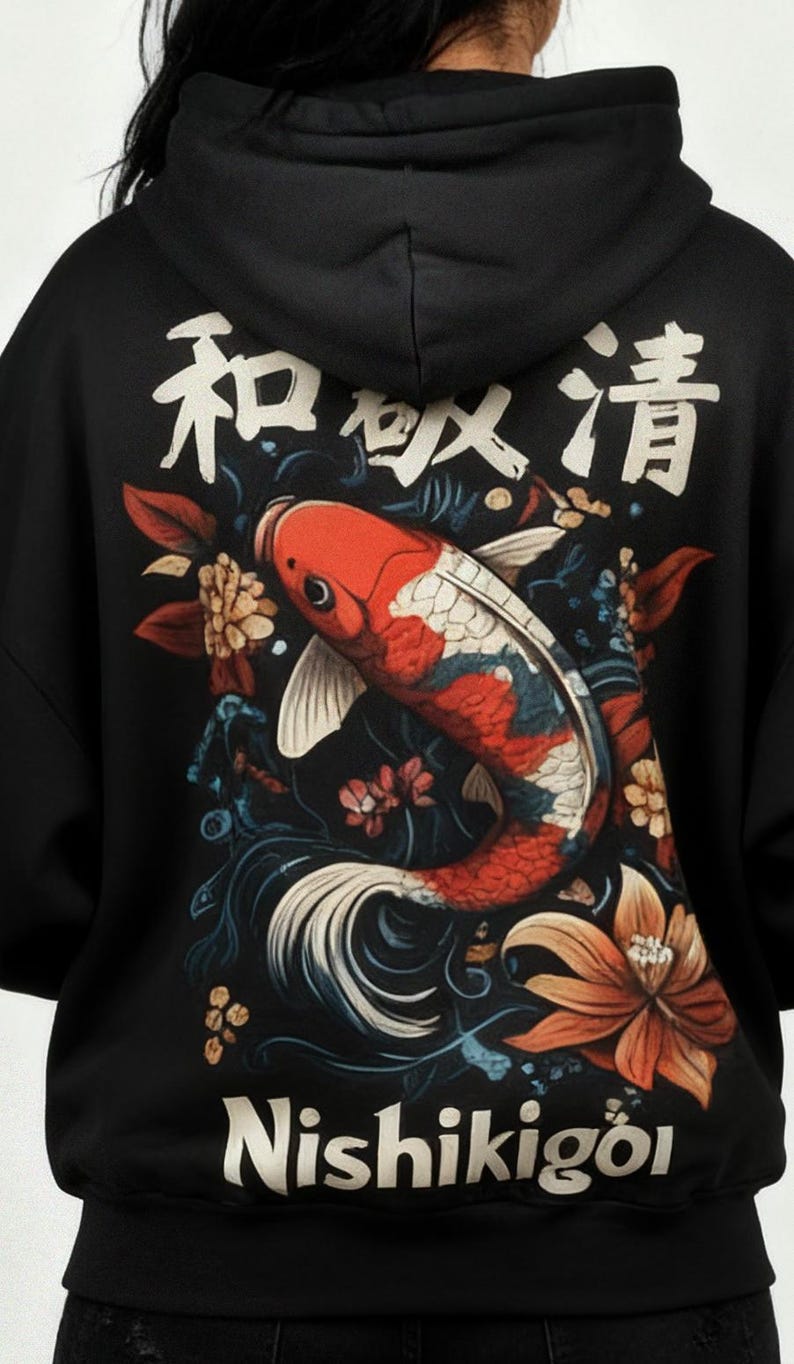 Pu&ograve; includere: Felpa con cappuccio nera con un'illustrazione di una carpa koi con scaglie rosse, bianche e blu, circondata da elementi floreali. Caratteri giapponesi e la parola "Nishikigoi" sono stampati.