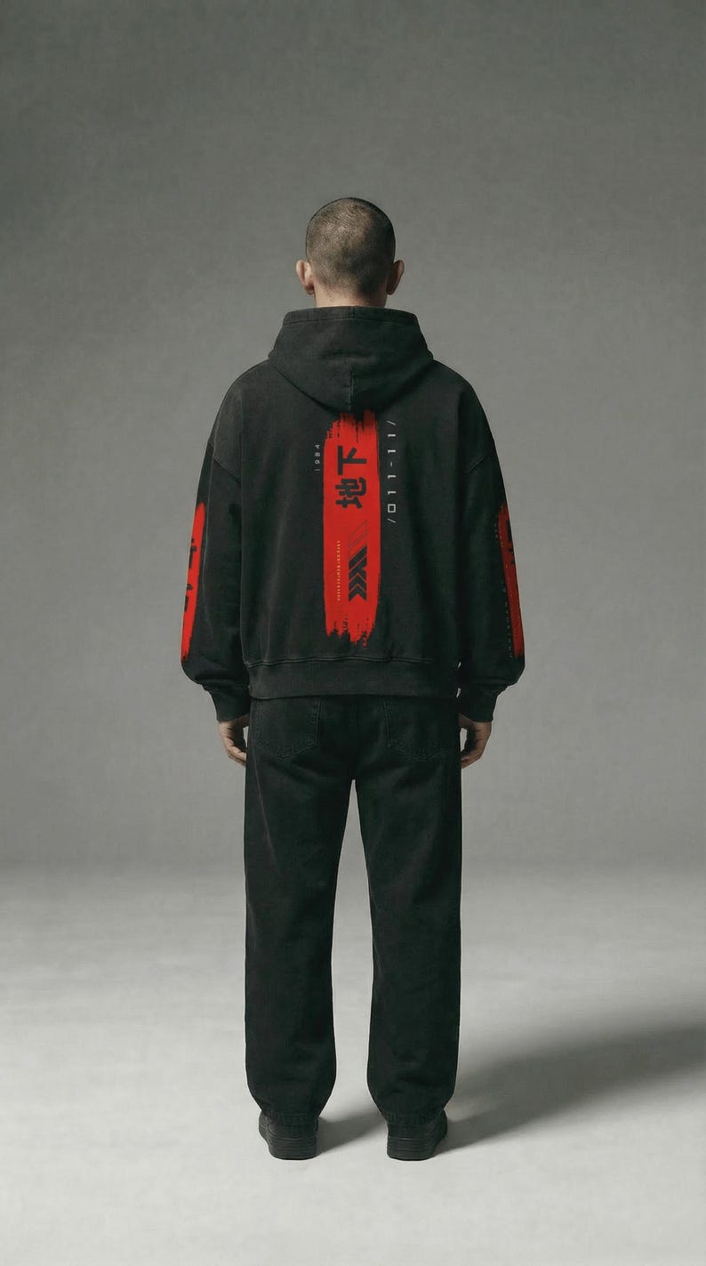 May include: Black hoodie and trousers. The hoodie has red Japanese text and a red brushstroke design on the back, with red accents on the sleeves. The outfit is worn by a person.