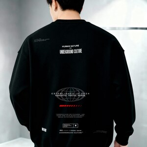 May include: A black long-sleeve sweatshirt featuring white text that reads HUMAN NATURE UNDERGROUND CULTURE, ESTABLISHED IN 2024 TORONTO, TOKYO, PARIS, and additional small graphic details including a red horizontal bar and a small skull icon.