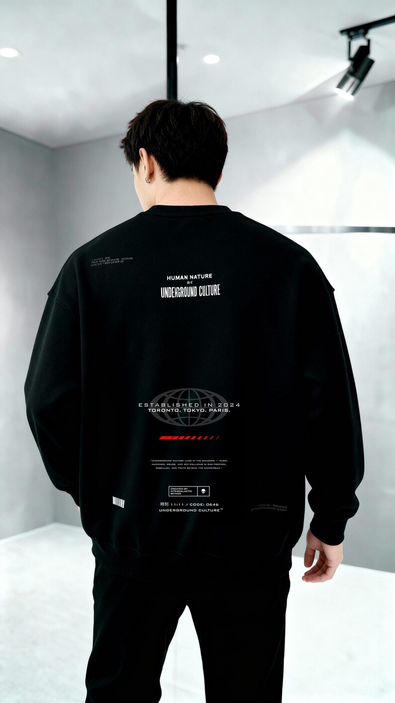May include: A black long-sleeve sweatshirt featuring white text that reads HUMAN NATURE UNDERGROUND CULTURE, ESTABLISHED IN 2024 TORONTO, TOKYO, PARIS, and additional small graphic details including a red horizontal bar and a small skull icon.