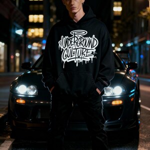 May include: A black hooded sweatshirt featuring the white text "UNDERGROUND CULTURE" in a stylized graffiti font with a halo graphic above the lettering. The hoodie includes a front kangaroo pocket and long sleeves with ribbed cuffs.