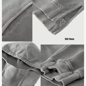 May include: Close-up details of a gray hoodie made from 100% premium cotton. Features include a turtleneck, thumb holes, and a slit hem. The fabric appears soft and textured.