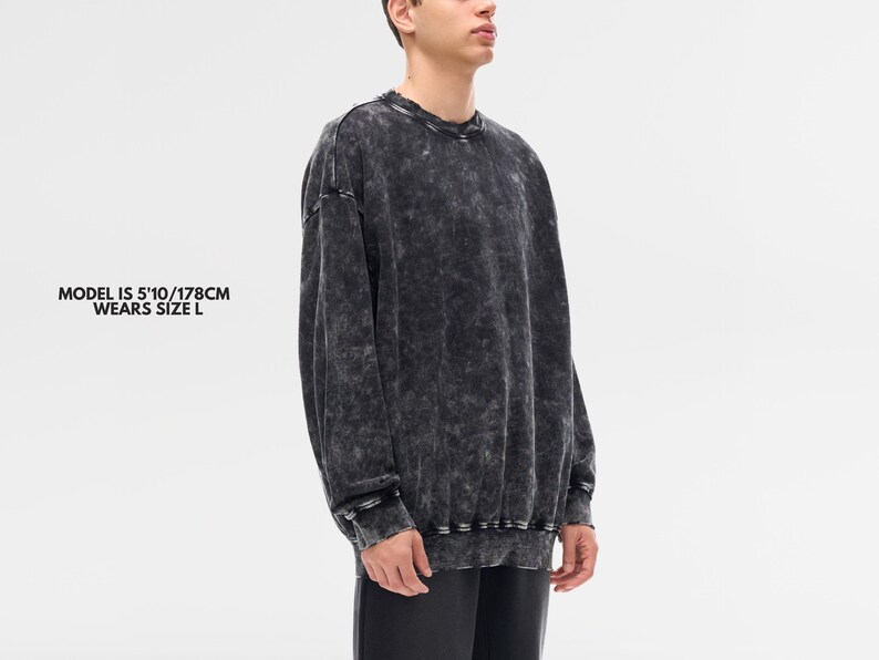 May include: A dark gray, acid-wash style sweatshirt with long sleeves. The garment has a crew neck and ribbed cuffs and hem. The model in the image is 5'10" (178cm) and wears a size L.