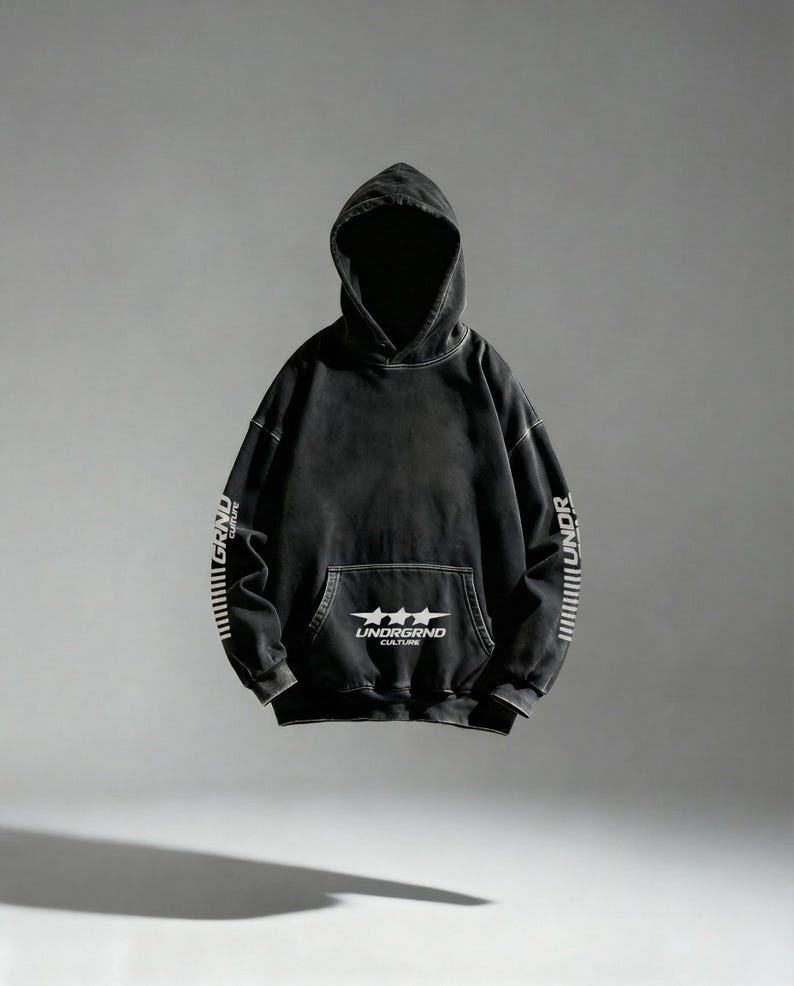 May include: Black hoodie with a front pocket and a hood. The hoodie has white text on the sleeves and a graphic on the front pocket that reads "UNDRGRND CULTURE". The hoodie is a dark, faded color.
