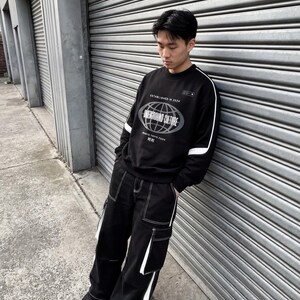 May include: A black long-sleeve sweatshirt featuring a white globe graphic and the text "UNDERGROUND CULTURE" with "ESTABLISHED IN 2024" above it. Paired with black cargo trousers featuring white contrast stitching and white side panel details.