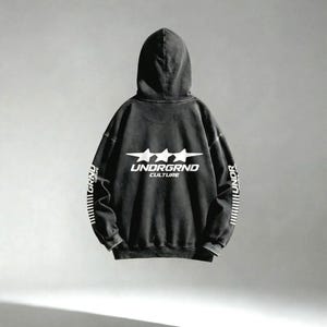 May include: A black hoodie with the text "UNDRGRND CULTURE" in white, along with three white stars. The sleeves have vertical white text and lines. The hoodie has a vintage, worn look.