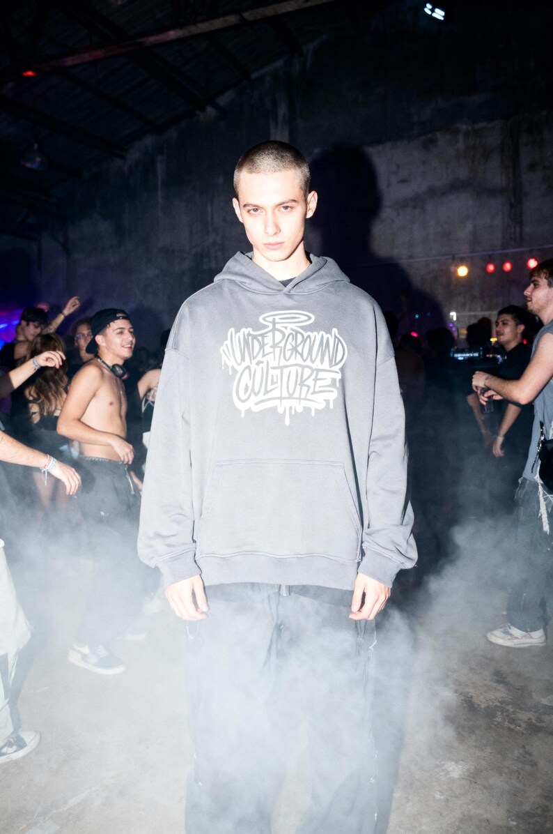 May include: A charcoal gray hooded sweatshirt featuring a front kangaroo pocket and a white graphic print on the chest that reads "UNDERGROUND CULTURE" in a stylized graffiti font with a halo above the text and dripping paint effects.
