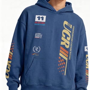 May include: Blue hoodie with "UCR" and "Underground Culture Racing" graphics in gold and orange. Features a front pocket and the number "11" on the chest. The sleeves have additional graphics. A casual streetwear style.