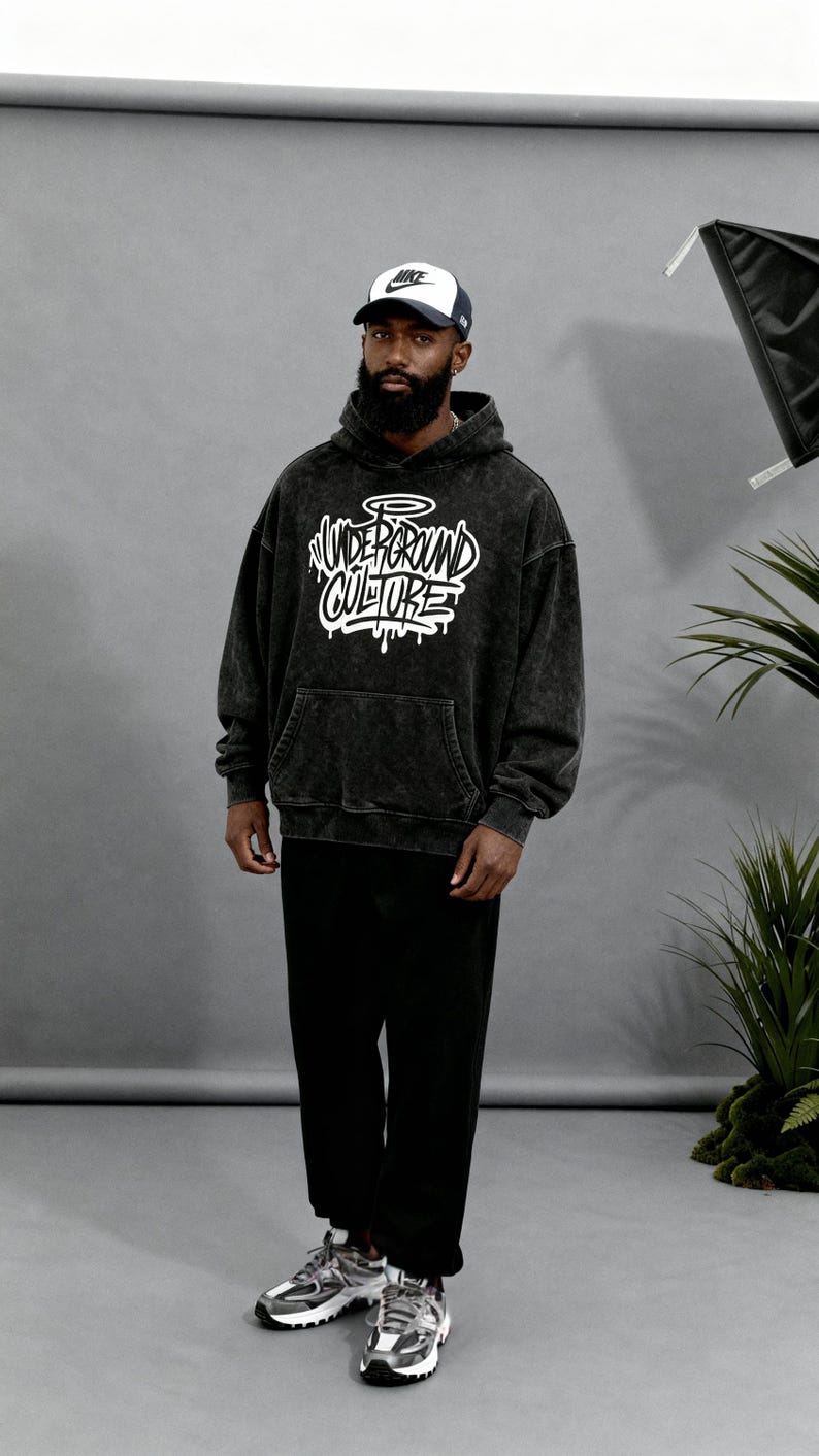 May include: A black acid-wash hooded sweatshirt featuring the white text "UNDERGROUND CULTURE" in a graffiti-style font on the chest, paired with black trousers, a white and black baseball cap, and grey and black athletic sneakers.