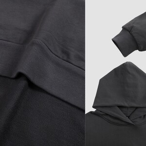 May include: A dark gray hooded sweatshirt with a ribbed hem and cuffs. The sweatshirt is made of a soft, comfortable fabric.