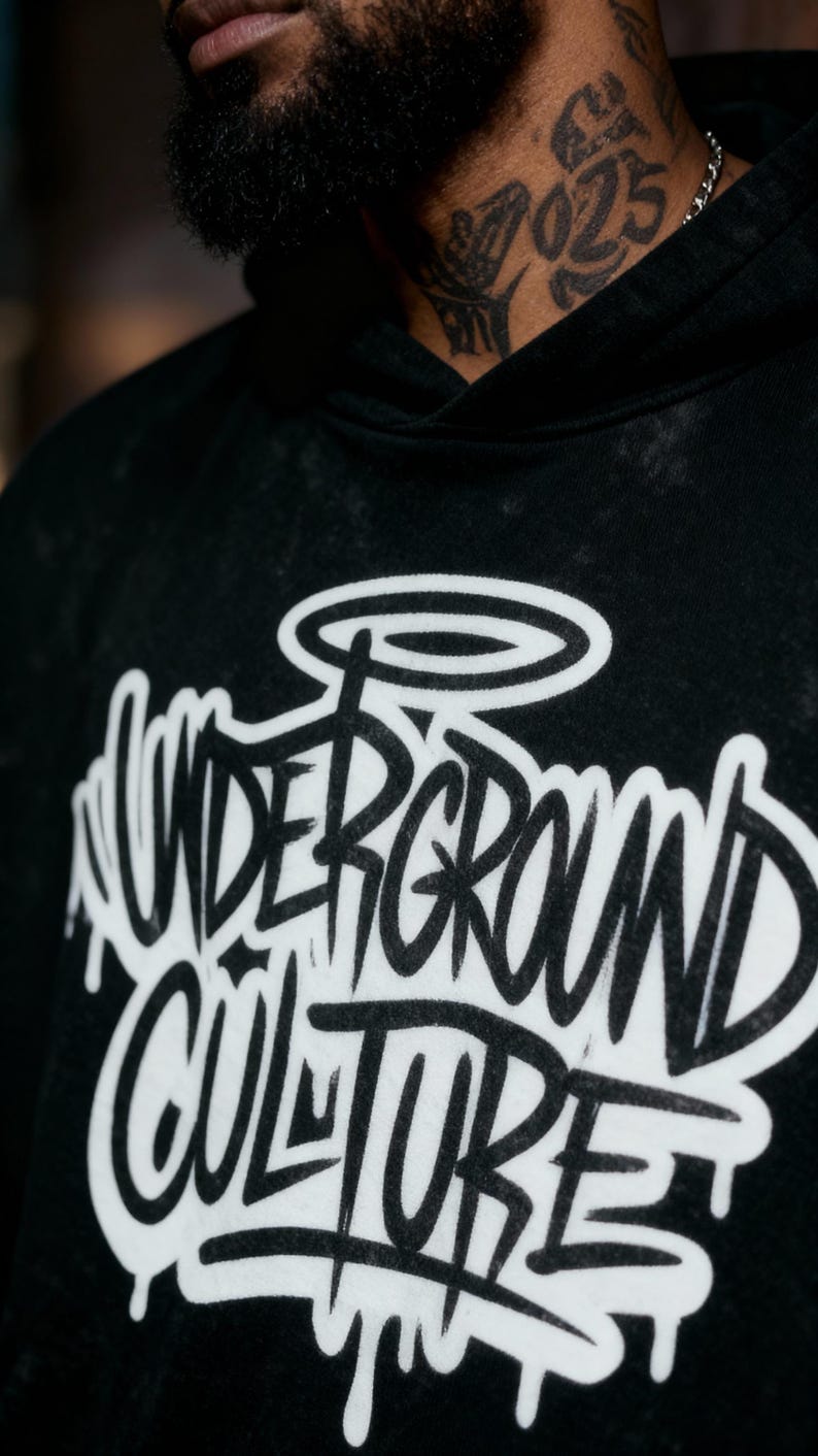 May include: A black hooded sweatshirt with a washed, faded texture. The front features large, white, graffiti-style lettering that reads "UNDERGROUND CULTURE" with a halo graphic above the text. The design has a dripping paint effect.
