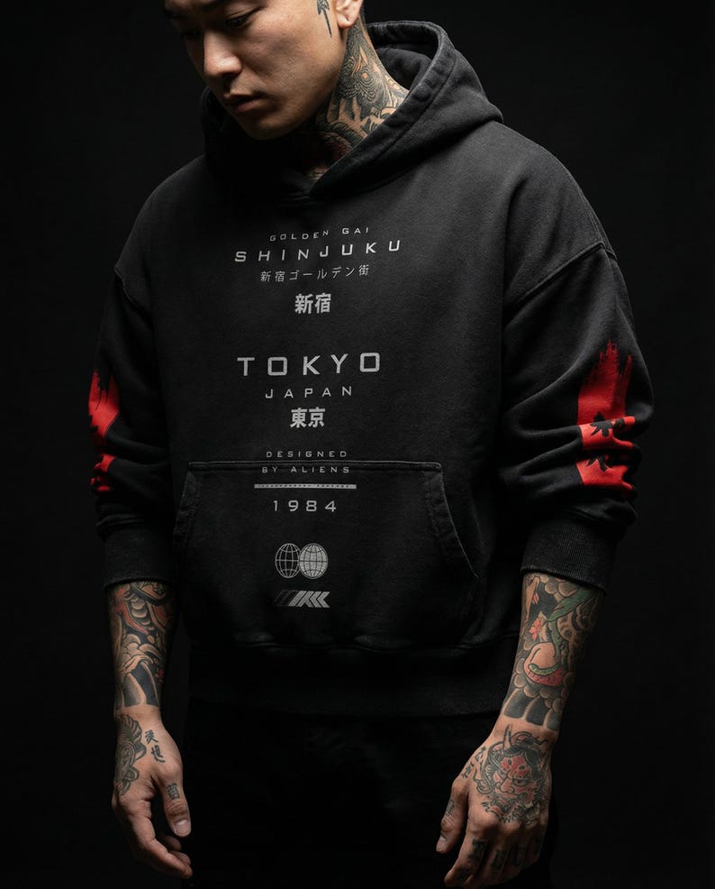 May include: Black hoodie with white and red graphics. The front of the hoodie features the text "GOLDEN GAI SHINJUKU" and "TOKYO JAPAN". The sleeves have red accents. The hoodie also has a front pocket and the year "1984" printed on it.