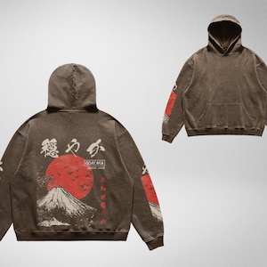 May include: A brown hoodie with a Japanese mountain scene and red sun graphic on the back. The hoodie has the text "GOAYAKA" and "SIMPLE - CALM" printed on the back. The sleeves have a repeating pattern of Japanese characters.