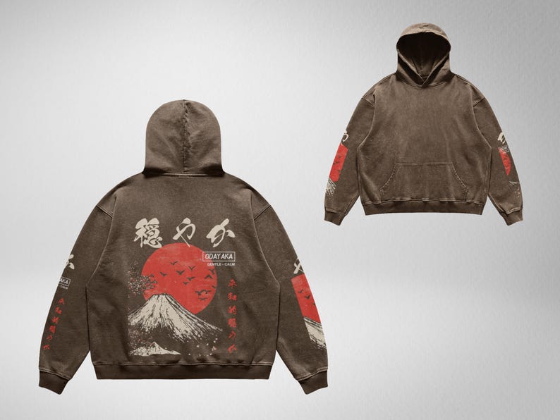 May include: A brown hoodie with a Japanese mountain scene and red sun graphic on the back. The hoodie has the text "GOAYAKA" and "SIMPLE - CALM" printed on the back. The sleeves have a repeating pattern of Japanese characters.