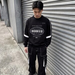 May include: A black long-sleeve sweatshirt with white sleeve stripes and a graphic featuring a globe, the text "ESTABLISHED IN 2024" and "UNDERGROUND CULTURE," paired with black cargo trousers featuring white contrast stitching and white side panels.