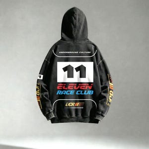 May include: Black hooded sweatshirt with the text "UNDERGROUND CULTURE" above a white rectangle with the number "11" in black. Below, the text "ELEVEN RACE CLUB" is in red and blue. The sleeves have colorful racing-themed graphics.