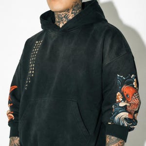 Pu&ograve; includere: Felpa con cappuccio nera con tasca frontale e cappuccio con coulisse. Le maniche presentano un design di carpa koi con accenti arancioni, rossi e blu. Testo giapponese stampato sul lato sinistro. La felpa &egrave; realizzata in un materiale morbido e confortevole.