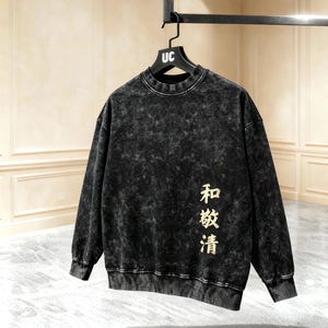 May include: Black acid wash sweatshirt with the text "和敬清" in gold lettering. The sweatshirt has a crew neck and long sleeves. The hanger has "UC" printed on it.