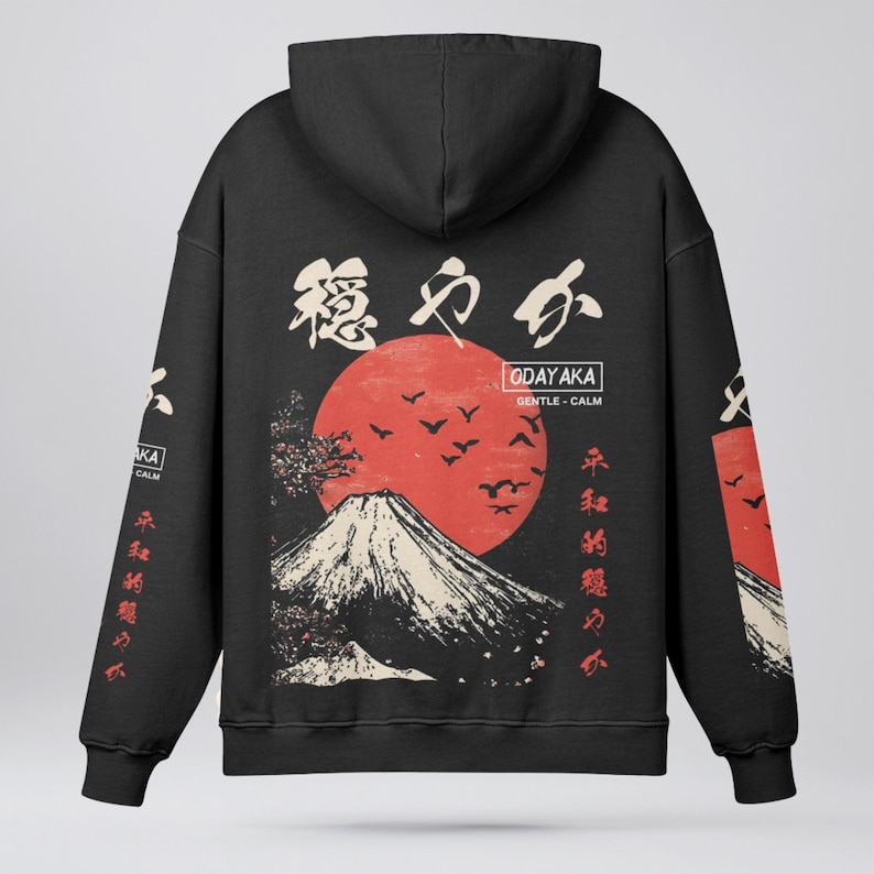 May include: Black hoodie with a Japanese-inspired design featuring a red sun, a mountain, and Japanese characters. The text on the hoodie reads "ODAYAKA GENTLE - CALM".