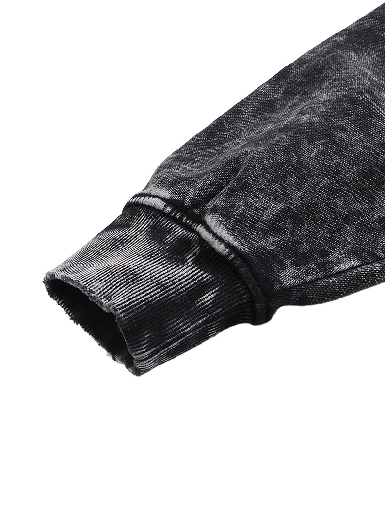May include: Close-up of a black and gray acid wash sweatshirt sleeve. The cuff is ribbed and has a distressed, worn look. The fabric has a textured appearance with a faded, mottled pattern.