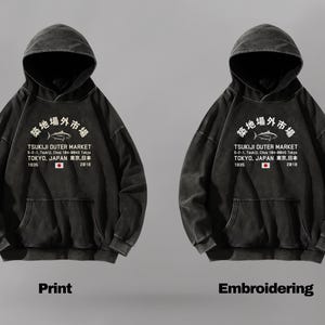 May include: A black hooded sweatshirt featuring a white graphic print of a fish and the text Tsukiji Outer Market, 5-2-1, Tsukiji, Chuo 104-0045 Tokyo, Tokyo, Japan, 1935, 2018, and a small Japanese flag. The text Print and Embroidering appear below.