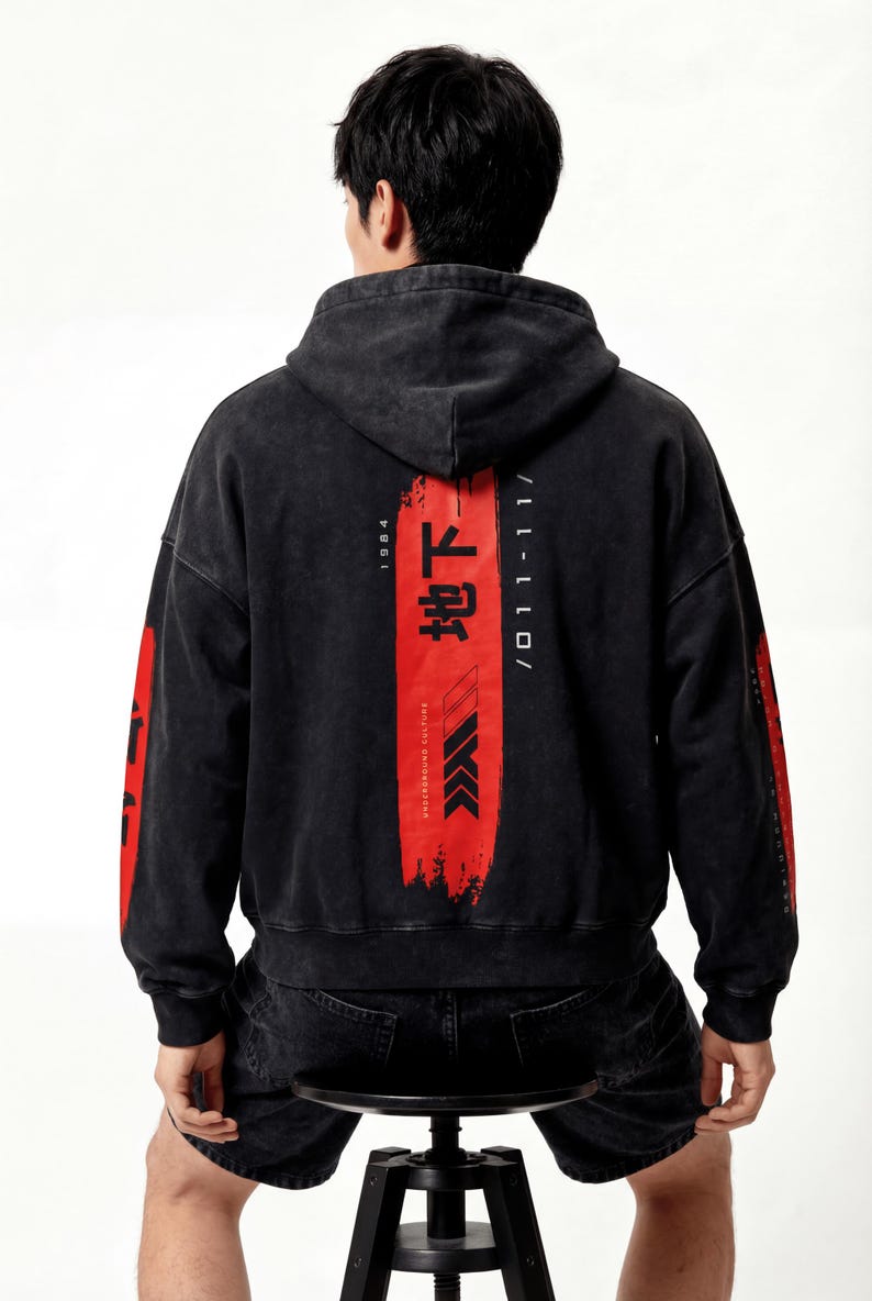 May include: Black hooded sweatshirt with red graphic elements and Japanese text on the back. The design includes vertical text and arrows. The sleeves also have red accents. The sweatshirt is made of a washed, textured fabric.