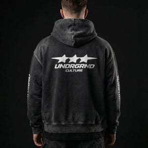 May include: A dark gray hoodie with a faded, vintage look. The back features the text "UNDRGRND CULTURE" in white, with three star graphics above the text. The sleeves also have white text. The hoodie has a drawstring hood.