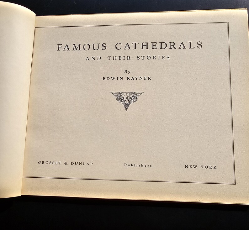 Op de afbeelding: Open boekpagina met de titel "FAMOUS CATHEDRALS AND THEIR STORIES" in een schreefletter. De auteur is Edwin Rayner. De uitgever, Grosset & Dunlap, en de stad New York staan onderaan de pagina.